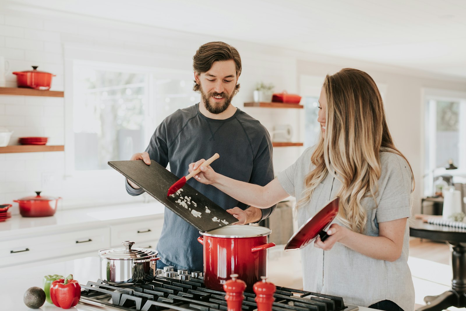 Two people cooking together at a stove in a bright kitchen.